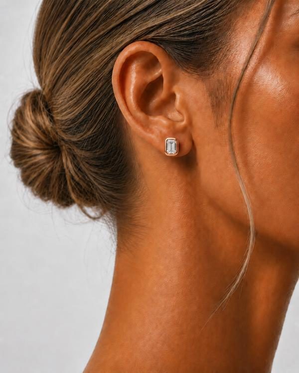 Emerald cut diamond bezel stud in rose gold, worn on the ear