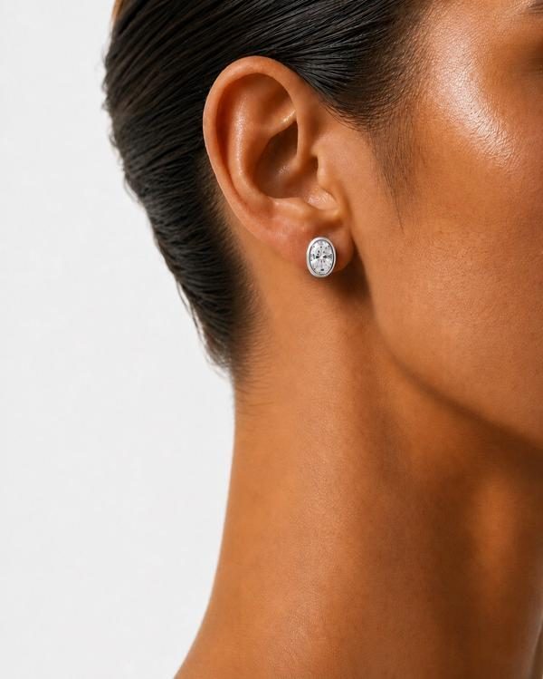 Oval diamond bezel stud in white gold, worn on the ear