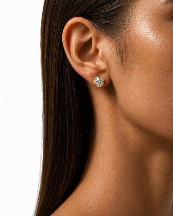Round diamond bezel stud in yellow gold, worn on the ear