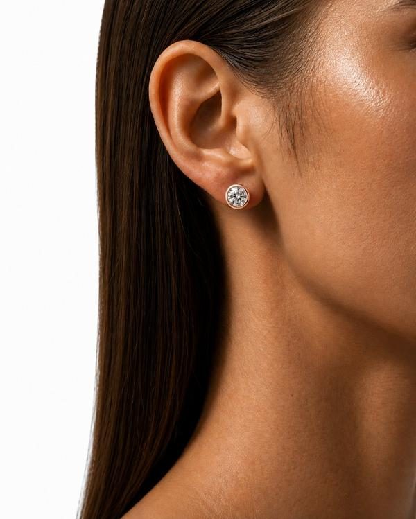 Round diamond bezel stud in rose gold, worn on the ear