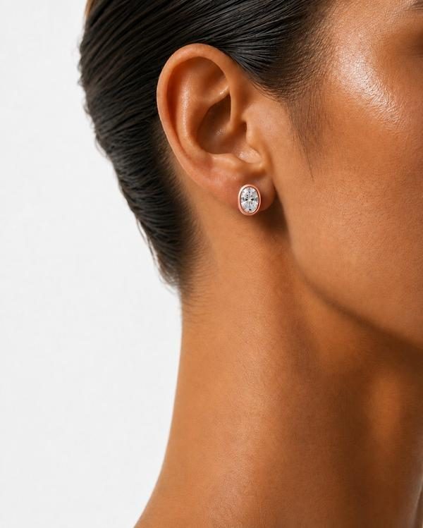 Oval diamond bezel stud in rose gold, worn on the ear