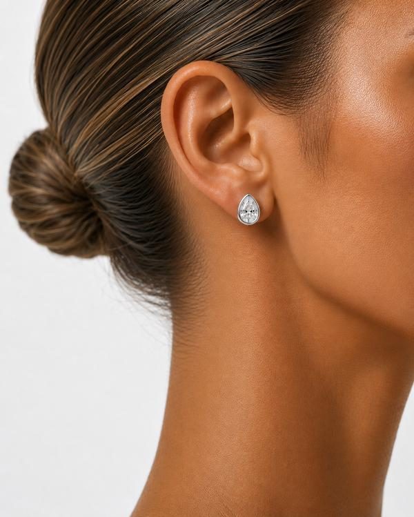 Pear diamond bezel stud in white gold, worn on the ear
